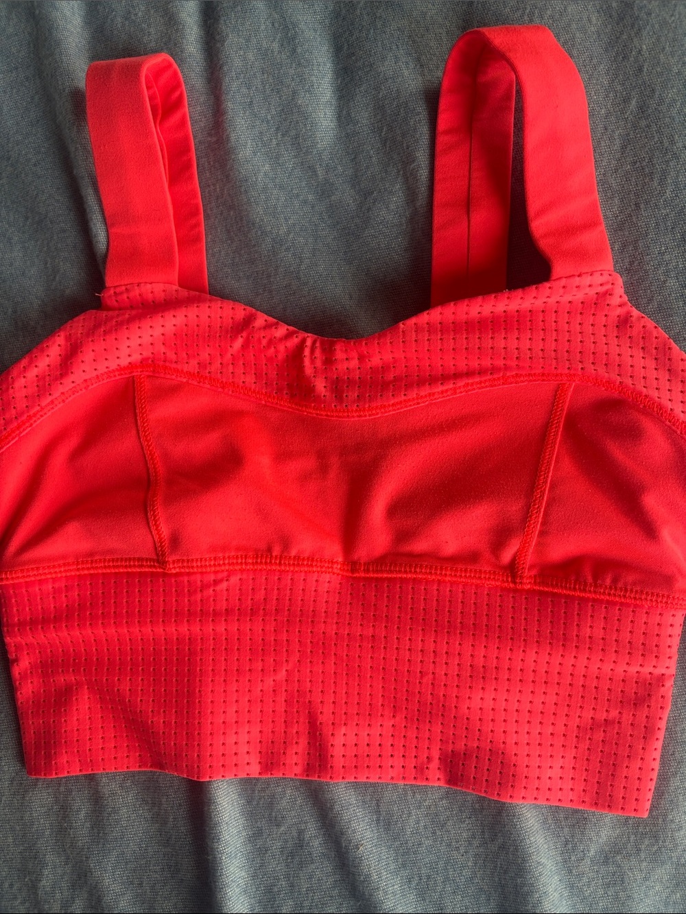 Bright coral-red Lululemon sports bra with breathable perforated mesh detailing